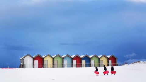 dpatopbilder - 05.01.2026, Großbritannien, Blyth: Menschen genießen die winterlichen Bedingungen vor bunten Strandhütten. Foto: Owen Humphreys/PA Wire/dpa +++ dpa-Bildfunk +++